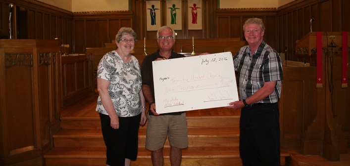 Bracebridge author Paul Arril presents a cheque for $1,000.00 to Will Gibson, Chair of the Trinity United Church Finance Committee and Joanne Purchase, Chair of the Church Council.