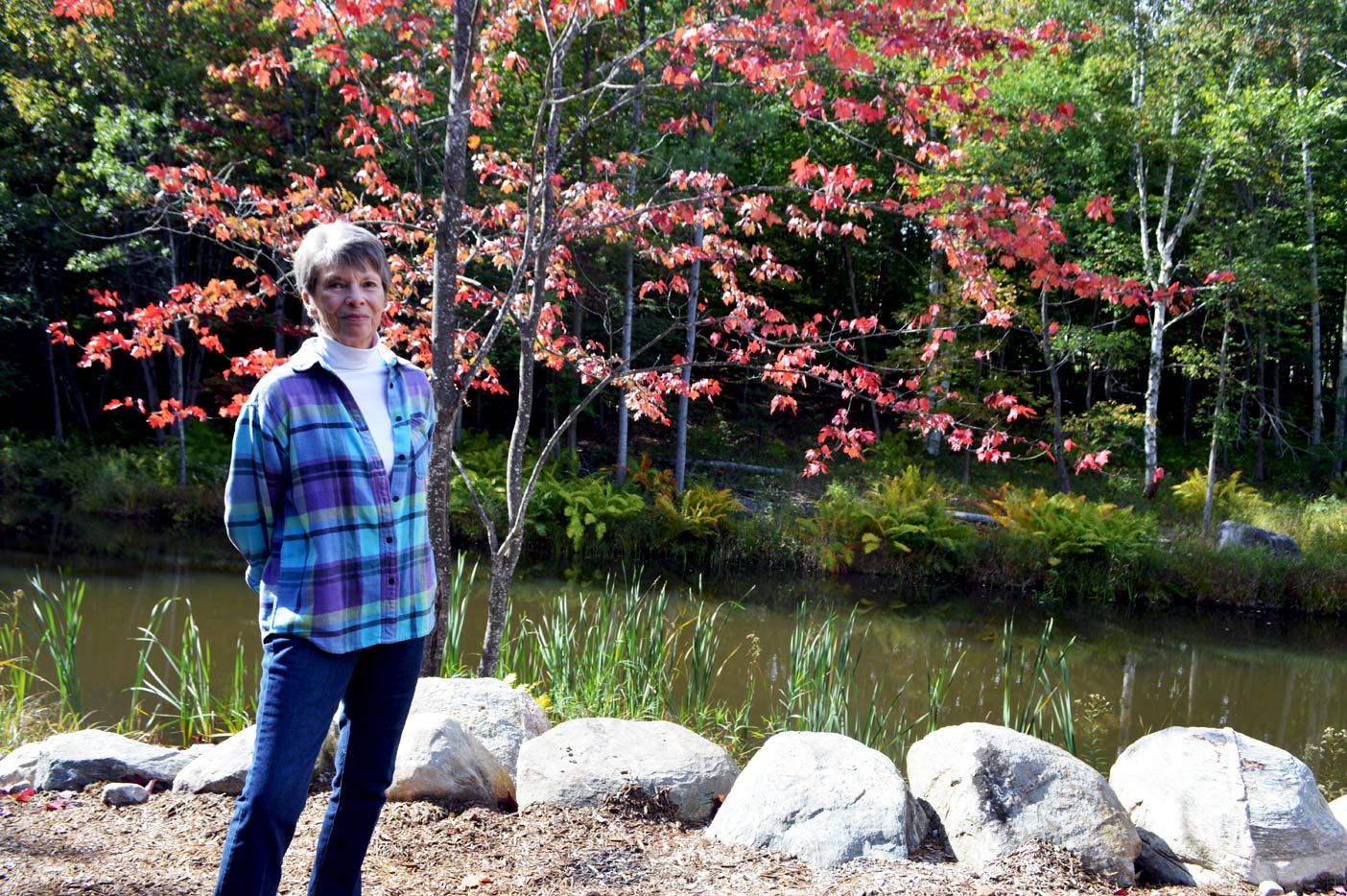 Mary has always had an affinity for the great outdoors. Here she stands in front of the beautiful spring-fed pond on her unique town property.
