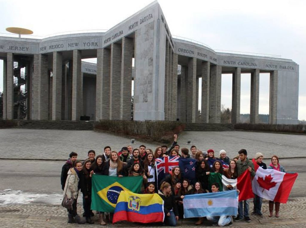 Rotary Youth Exchange students from across the globe gather for a photo op with the flags of their countries at the American War Memorial in Bastogne, Belgium 