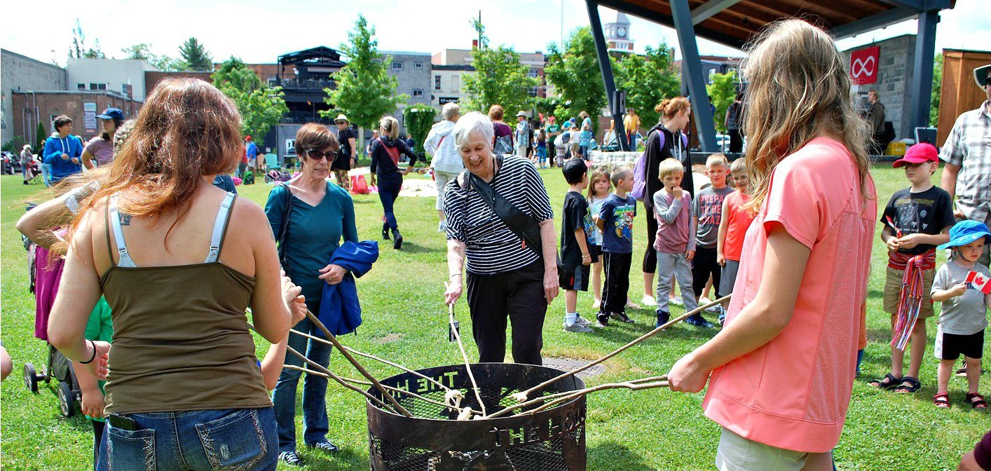 Guests at the First Nations, Métis and Inuit Celebration  cook bannock over a fire