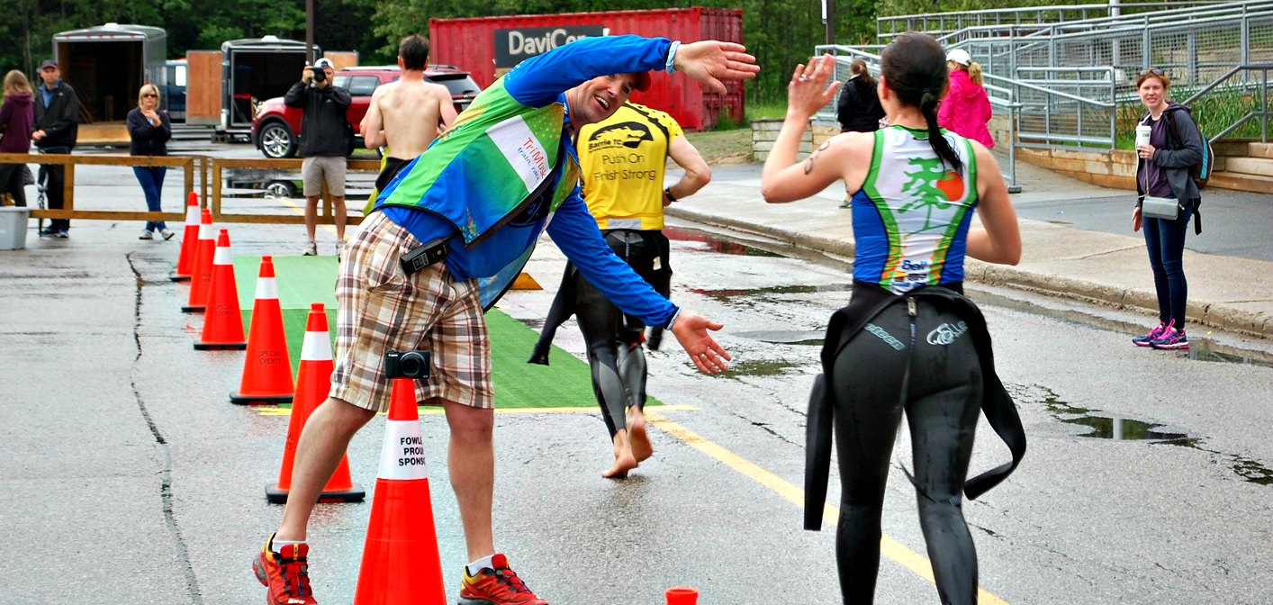TriMuskokan co-director Rich Trenholm high-fives swimmers on their way into the transition area