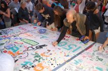 Rudi Stade (right) adds his mark to a community art piece