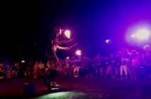 The Fire Guy zips past the crowd on a motorized board while juggling a flaming devil stick