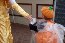 Cinderella aka Kaiya Roberson gives a bag of Nutty Chocolatier treats to pumpkin Thea McCready