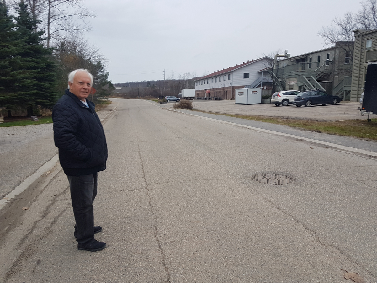 Bob Masterson stands in front of the manhole cover on Szawlowski Drive from where there was sewage flooding the road on October 28.