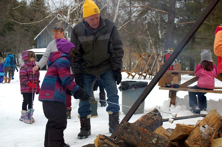 Selah Brown (left) learns the finer points of marshmallow roasting from Rotarian Cameron White