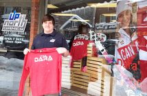 Kade Nelson holds up a Team Dara shirt in front of Up North Games
