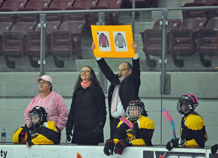 Hoyas Coach Brian Webb holds up a sign to thank the game's refs for their support. Webb sported a suit and pink tie for the game.