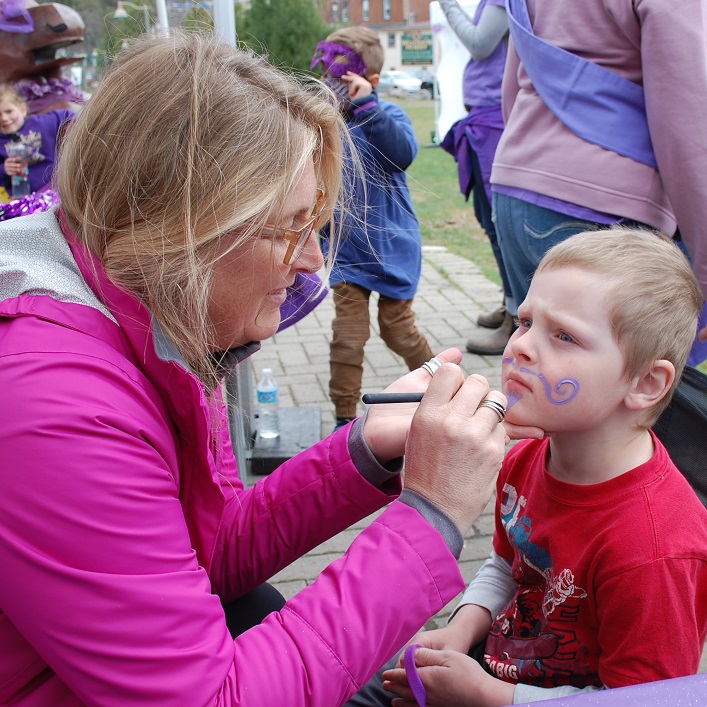 Volunteer Kelly Burmeister gives Cody Dingman a new purple look for Hike for Hospice