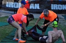 Ironman volunteers help strip wet suits from athletes as they exit the swim course