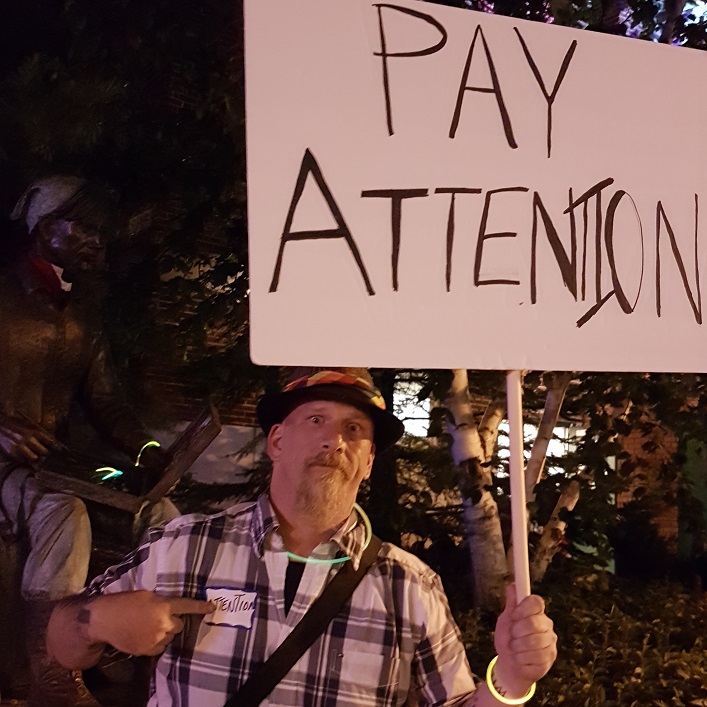 Tim wants you to 'PAY ATTENTION'. His nametag says ATTENTION.