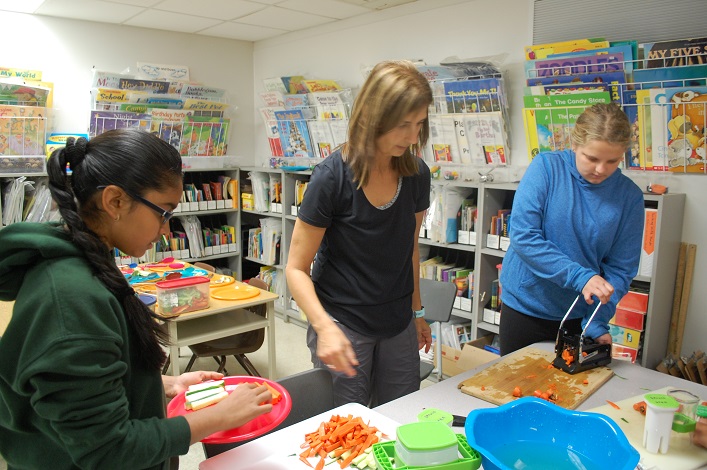 Spruce Glen breakfast program student volunteers Tryaksha Mahate (left) and Emma Campbell-Stoneburgh help parent volunteer Katherine Andrews prepare plates of vegetables to go to each of the school's classrooms