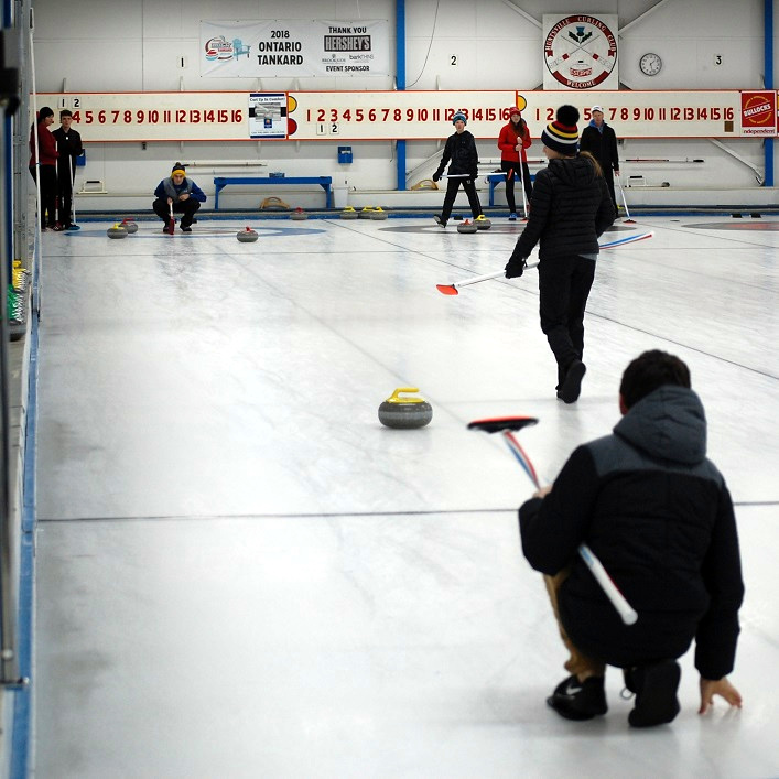 Zach Belfry (back) marks the shot for Ben Caplan (foreground) while Stella Keay gets ready to sweep