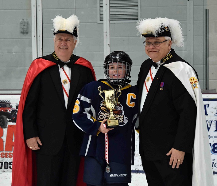 Team captain Hunter Stillar accepts the silver cup from members of the Knights of Columbus