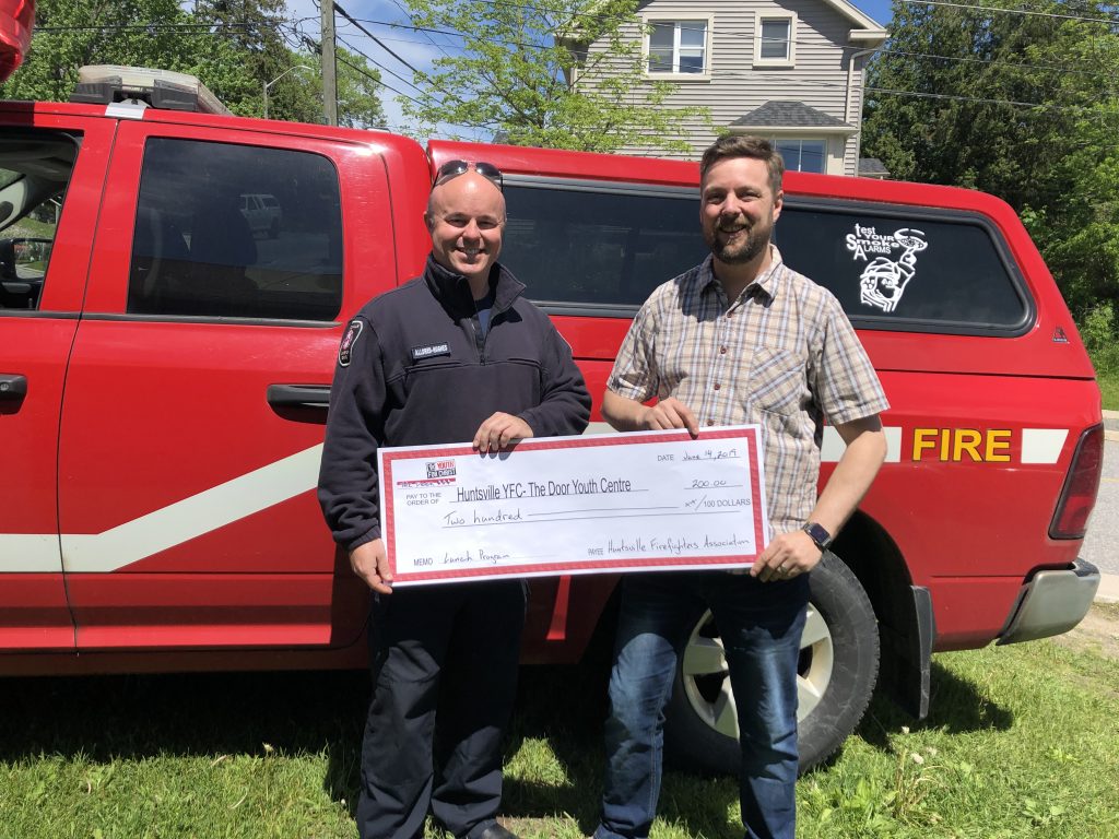 Jeremy Alldred-Hughes, President of the Huntsville Firefighters' Association presents a cheque to James Hunt, Director of The Door
