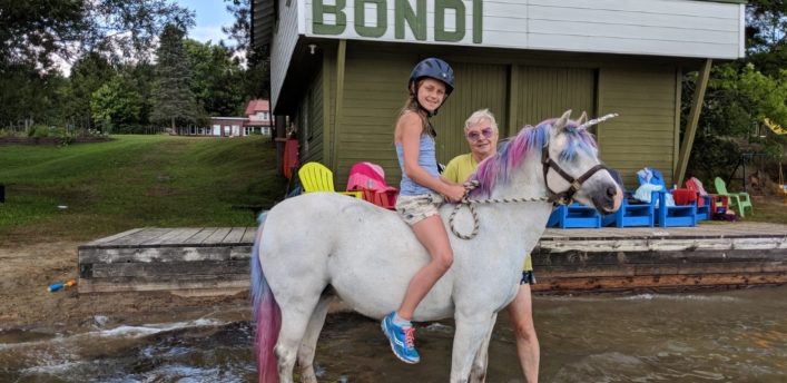 Snowbird the unicorn, who was magicked into reality by Nancy Tapley (back), takes Adrianna Lulich for a ride