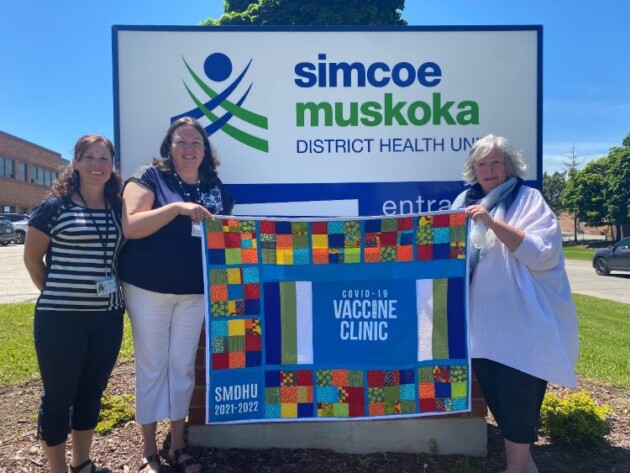 COVID-19 vaccination clinic volunteer presents commemorative quilt to the health unit